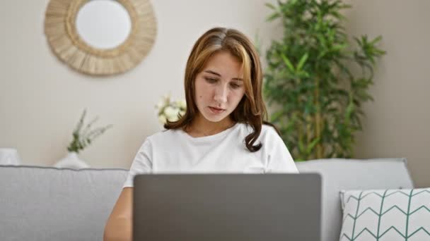 年轻女子坐在沙发上 手里拿着笔记本电脑和信用卡购物 — 图库视频影像