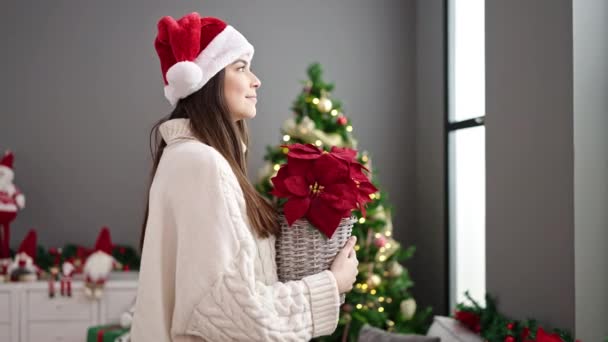 Νεαρή Όμορφη Ισπανόφωνη Γυναίκα Κρατώντας Φυτό Στέκεται Δίπλα Στο Χριστουγεννιάτικο — Αρχείο Βίντεο