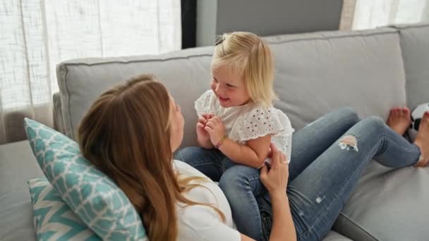 コーカサス人の母親と小さな娘はお互いをくすぐり ソファーに横たわり 居心地の良い家でたくさん笑った — ストック動画