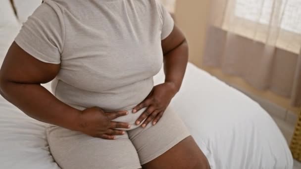 非洲裔美国妇女 坐在床上 月经剧痛 在室内与腹痛作斗争 — 图库视频影像