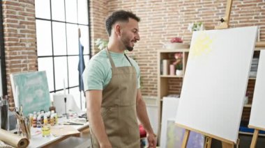 Genç Arap ressam resim stüdyosunda resim çektirirken görüntülü arama yapıyor.