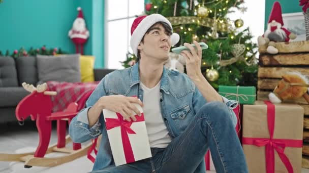 Young Hispanic Man Holding Christmas Gift Sending Voice Message Smartphone — Stock Video
