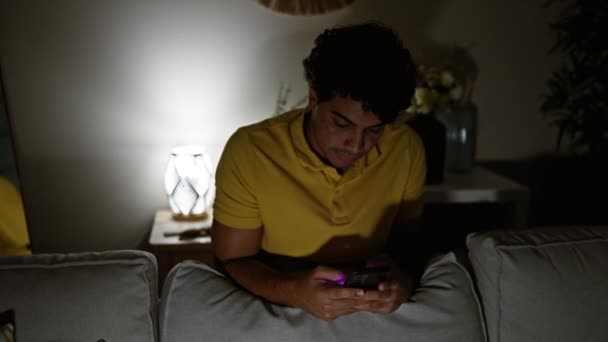 Genç Latin Adam Akıllı Telefon Kullanıyor Evdeki Kanepeye Yaslanıyor — Stok video