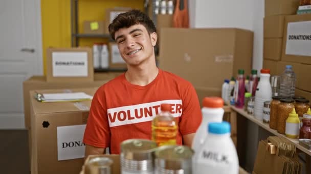 年轻而自信的他惊慌失措的少年微笑着 一边在一个热闹的慈善中心做义工 一边举起大拇指 承认自己的伟大工作 — 图库视频影像