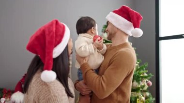 Evde Noel ağacının yanında duran bir çift ve oğlu balo düzenliyor.