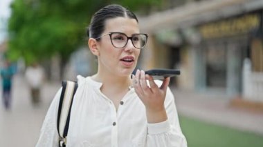 Genç, güzel İspanyol kadın sokakta akıllı telefonuyla sesli mesaj yolluyor.