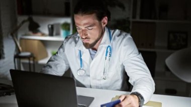Genç İspanyol doktor, klinikten laptop ve kredi kartıyla alışveriş yapıyor.