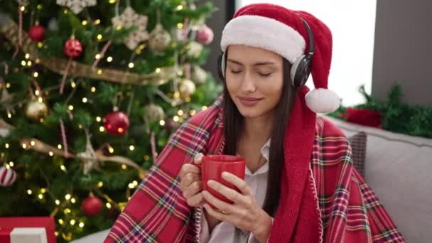 若いです美しいですヒスパニック女性リッスンに音楽を飲むコーヒー祝うクリスマス ホーム — ストック動画