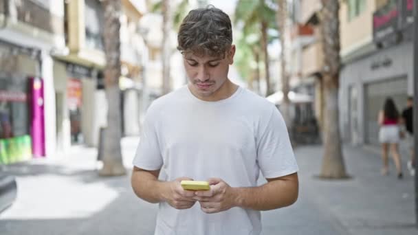 Νεαρός Ισπανός Που Χρησιμοποιεί Smartphone Χαμογελώντας Στο Δρόμο — Αρχείο Βίντεο