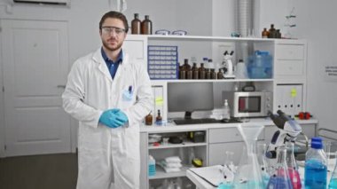 Genç İspanyol bilim adamı gülümseyerek laboratuvarda yürüyor.