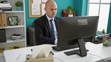 Genç İspanyol iş adamı ofiste hapşıran bir bilgisayar kullanıyor.