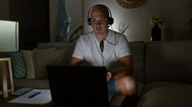 Latin asıllı genç bir adam video görüşmesi yapıyor. Evde kulaklıkları çıkarıyor.