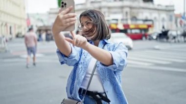 Genç ve güzel İspanyol kadın Viyana sokaklarında akıllı telefonuyla selfie çekiyor.