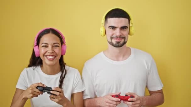 笑美丽的夫妇 玩电子游戏 一起笑 在一个阳光灿烂的黄色孤立的背景上创造回忆 — 图库视频影像