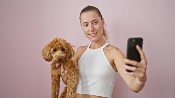 Молодая Белая Женщина Собакой Улыбается Обнимаясь Помощью Смартфона Изолированном Розовом — стоковое видео
