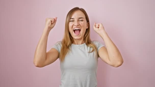 孤立したピンクの背景に喜びの笑顔で祝う自信のある若いブロンドの女性 — ストック動画