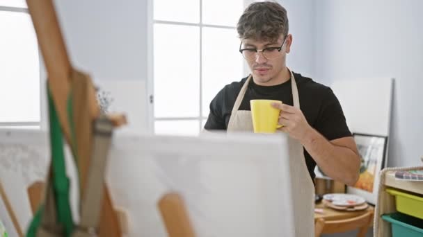 앞치마를 히스패닉 예술가 스튜디오에서 자신의 그림을보고있는 커피를 마시는 — 비디오