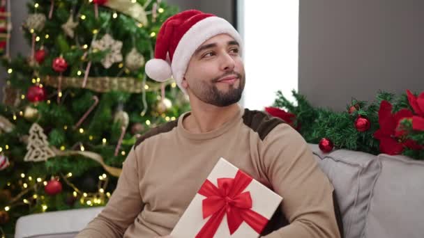 Mladý Arabky Muž Drží Dárek Sedí Pohovce Vánočního Stromečku Doma — Stock video