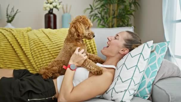 自宅で遊んでいるソファーに横たわる犬と若い白人女性 — ストック動画