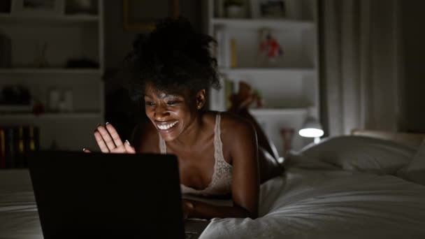 アフリカ系アメリカ人女性は寝室でベッドに横たわるビデオ通話を持つランジェリーを着用しています — ストック動画