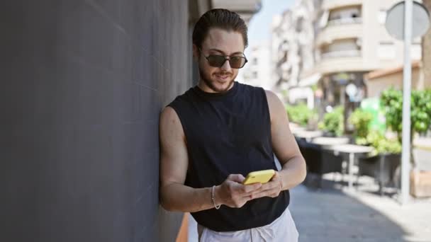 Junger Hispanischer Mann Mit Sonnenbrille Nutzt Smartphone Auf Der Straße — Stockvideo