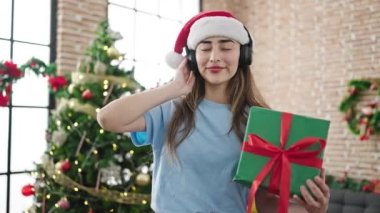 Genç ve güzel İspanyol kadın evde Noel 'i kutlamak için müzik dinliyor.