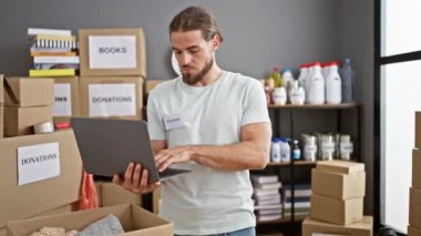 Genç İspanyol gönüllü yardım merkezinde dizüstü bilgisayar kullanarak ürünleri kontrol ediyor.