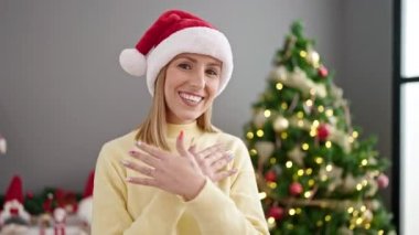 Genç sarışın kadın Noel ağacının yanında dans ediyor.