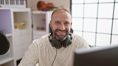 Büyüleyici genç müzisyen, kulaklıklar kulaklarını okşuyor bulaşıcı gülümsemesiyle bir müzik stüdyosunu şereflendiriyor. Melodinin, rahatlığın ve kendine güvenin neşeli bir karışımı..