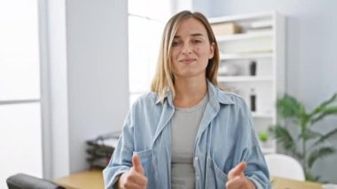 Kendine güvenen genç sarışın iş kadını, mutluluk saçan, ofiste iyi niyet gösteren hareketler yapan, başarıyı simgeleyen. Bu rahat ve pozitif işçinin güzel portresi, kendine güveni tam.