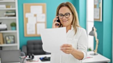 Ofisteki telefon okuma belgesinde konuşan orta yaşlı İspanyol iş kadını.