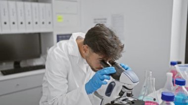 Genç Arap bilim adamı laboratuvarda mikroskop kullanıyor.