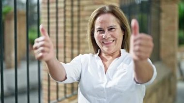 Orta yaşlı İspanyol kadın gülümsüyor. Kendine güveni tam. Başparmaklarıyla sokakları imzalıyor.