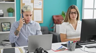 İki işçi kadın ve erkek birlikte çalışıyor. Ofiste akıllı telefondan konuşuyorlar.