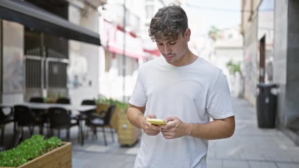 Joven Hombre Hispano Usando Smartphone Con Expresión Seria Terraza Cafetería — Vídeos de Stock