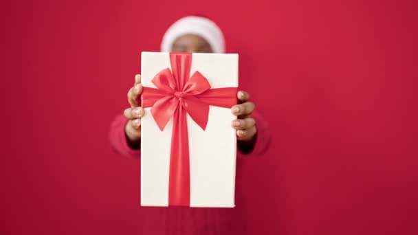 African American Woman Holding Gift Wearing Christmas Hat Isolated Red — Stock Video