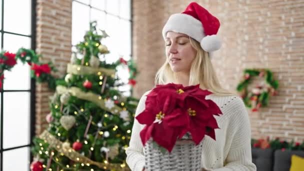Νεαρή Ξανθιά Γυναίκα Που Κρατάει Χριστουγεννιάτικο Φυτό Στο Σπίτι — Αρχείο Βίντεο