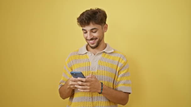 Bonito Jovem Árabe Confiantemente Mensagens Texto Seu Smartphone Sorrindo Alegremente — Vídeo de Stock