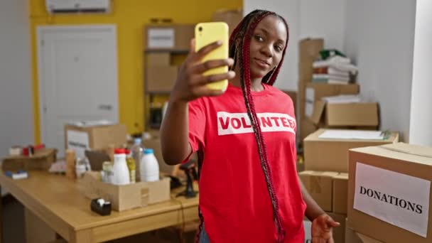 有自信的非洲裔美国女人 头戴辫子 一边在一个充满活力的慈善中心当义工一边打电话一边高兴地说话 — 图库视频影像