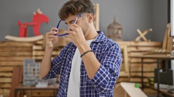 一个面容严肃 头戴耳机的年轻的阿拉伯男子在木工行业中施展他的魔法 一个专门精通木材业的专业人员在他的室内工作室里工作 — 图库视频影像