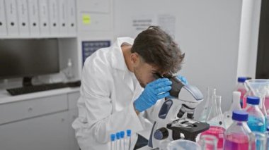 Yakışıklı, zor durumdaki genç Arap bilim adamı mikroskop kullanarak tedirgin edici tıbbi keşifler üzerine laboratuvarda üzgün.