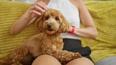 Köpekli beyaz bir kadın evdeki kanepede oturuyor.