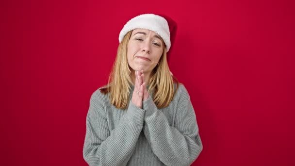 Молодая Блондинка Рождественской Шляпе Молится Скрещивает Пальцы Изолированном Красном Фоне — стоковое видео