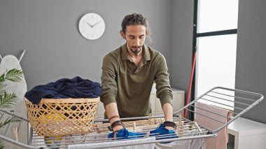 Çamaşır odasında çamaşır ipine elbise asan genç bir İspanyol.