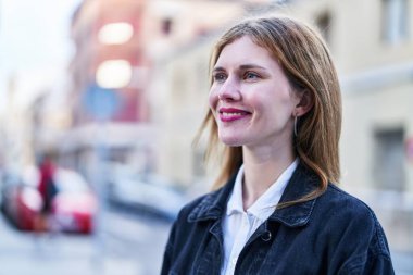 Young blonde woman smiling confident looking to the side at street