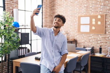 Genç Arap iş adamı ofisteki akıllı telefondan selfie çekiyor.