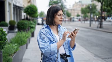 Genç ve güzel İspanyol kadın Viyana sokaklarında akıllı telefon kullanıyor.