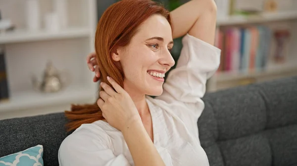 Young redhead woman relaxed on sofa smiling at home