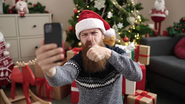 남자는 집에서 크리스마스 트리에 바닥에 스마트 폰으로 셀카를 만듭니다 — 스톡 사진