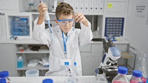 Adorable blond boy scientist working at laboratory, measuring liquid in test tube with pipette, a playful glimpse into future medical research.